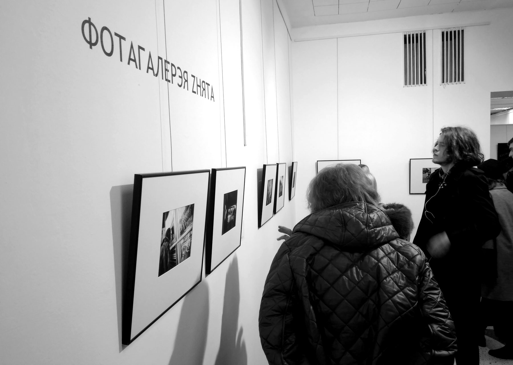 Visitors in front of a row of framed prints at the Autumn Salon 2018